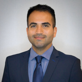 Ricardo Negron-Almodovar poses for a headshot wearing a blue suit, shirt and tie.