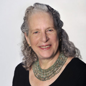 Sara Stuart smiles for her headshot, wearing black with a white background.