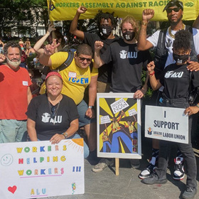 A group of organizers pose for a photo with their fists in the air at an Amazon Labor Union (ALU) action.