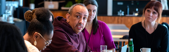 Adam Luna speaks at a table with fellows during the Narrative Innovators Lab.