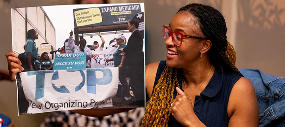 Brianna Brown holds an image of TOP organizers at a rally.