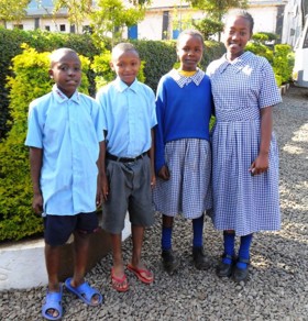 Children in the Nadine Griffey Academy stand smiling at the camera