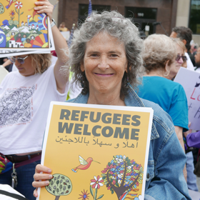 Woman holds "Refugees Welcome" sign