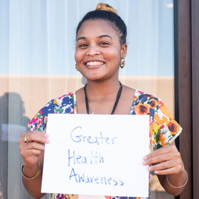 Woman holds "Greater Health Awareness" sign