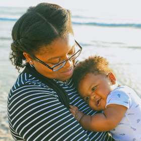 Black mom holds her baby smiling