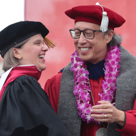 Vanessa Bechtel shakes hands and smiles with Dr. Richard Yao, wearing doctoral regalia