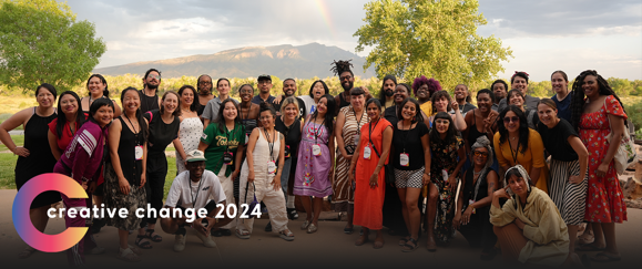 Creative Change 2024 group photo with a mountain and rainbow in background