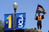 Protestor waves flag next to UCLA banner